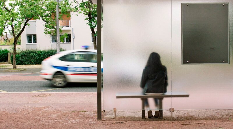 Die Bushaltestelle „Europe“ an der Ausfallstraße einer Stadt in Frankreich: Aus dem Bus steigt Zohra Hamadi, Metallstangen im Rücken. Sie geht aufrecht, kann endlich frei atmen. Doch Europa gewährt ihr nur ein paar Tage Gegenwart. Zohra, allein in einer sommerlich entleerten Welt, entscheidet sich dafür, nach der Zukunft zu greifen. Die Geschichte einer staatlich erzwungenen Fiktionalisierung. – Zohra beim Warten auf den Bus. – Bild: rbb/​Volker Sattel/​Pong Film GmbH