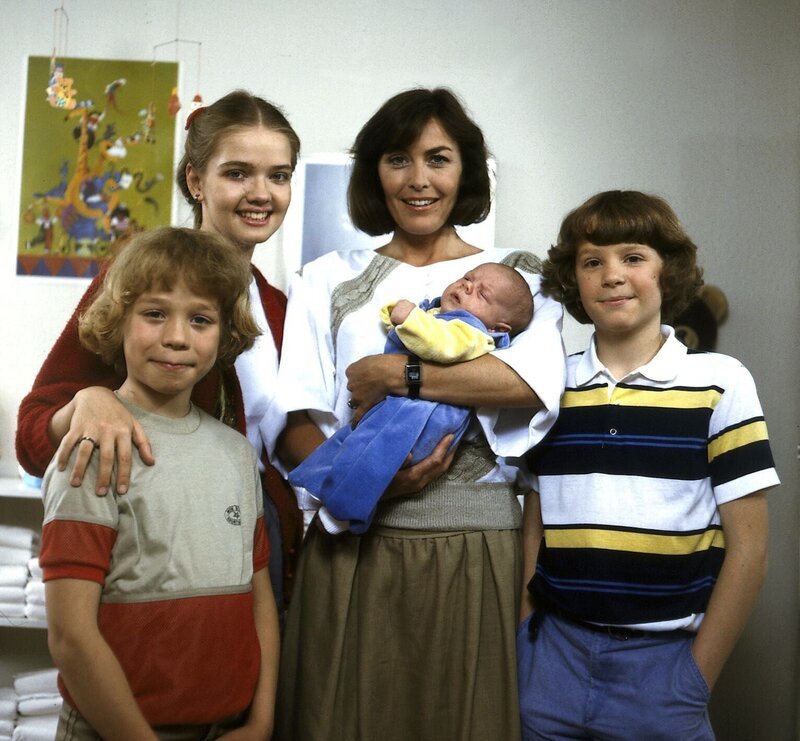 Die glückstrahlende Angi (Thekla Carola Wied, 2. v. r.) mit ihren älteren Kindern Markus (Timmo Niesner, l.), Tanja (Julia Biedermann, 2. v. l.) und Tom (Tarek Helmy, r.) wobei natürlich die jüngste, Franziska, nunmehr im Mittelpunkt steht. – Bild: Nova Film