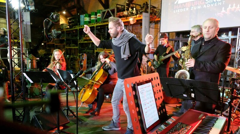 Der Arrangeur und Dirigent Niels Schröder mit der Begleitband. – Bild: NDR/​Jan Dieckmann