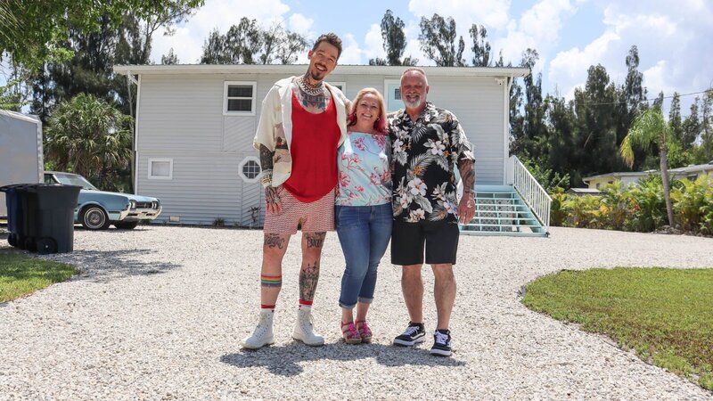 Host David Bromstad, Christine Gustafson, and Ken Gustafson, pose for picture outside of House 2, Nutgrass Nursery, as seen on My Lottery Dream Home, Season 16. – Bild: Warner Bros. Discovery, Inc.