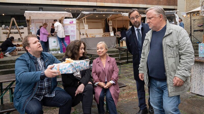 Zusammenkommen auf dem Straßenfest: Schrader (Björn Meyer) übergibt Thiel (Axel Prahl, r.) ein Geschenk. Boerne (Jan Josef Liefers, 2.v.r.), Alberich (ChrisTine Urspruch, m.) und Klemm (Mechthild Großmann, 2.v.l.) folgen dem Geschehen. – Bild: WDR/​Bavaria Fiction GmbH/​Thomas
