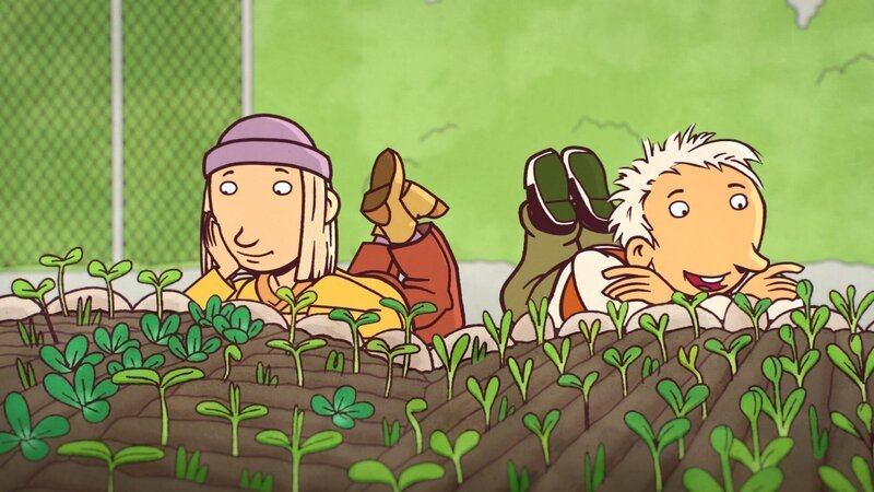 Sarah (links) und Oskar(rechts) liegen interessiert vor einem Blumenfeld und freuen sich, dass die Blumen anfangen zu wachsen. – Bild: WDR