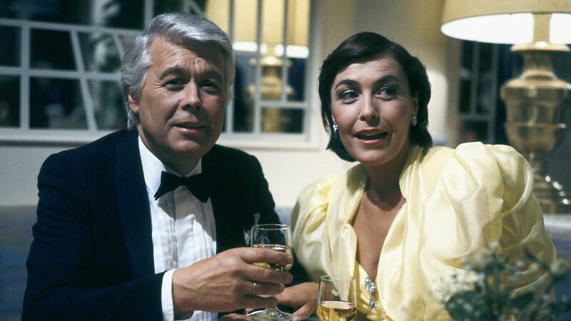 Angi (Thekla Carola Wied) und Werner (Peter Weck) beobachten als besorgtes Ehepaar auf einem Ball, wie Tanja sich auf dem Parkett bewegt. – Bild: ZDF und Barbara Oloffs/​Novafilm