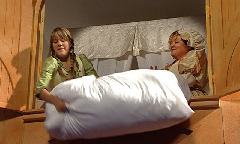 Frau Holle (Marianne Sägebrecht) und Marie Weber (Lea Eisleb) schütteln die Kissen aus. – Bild: rbb/​Sandor Domonkos