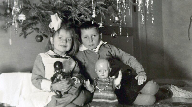 Lametta am Baum, der bunte Teller darunter – am 24. Dezember ging es früher wesentlich bescheidener zu. Die Kinder von damals erinnern sich nach einem langen Leben an die Weihnachtsfeste ihrer Kindheit und Jugend in bewegten Zeiten. Im Bild: Schwester und Bruder unterm Tannenbaum 1932. – Bild: BR/​SWR/​Brigitte Hoff