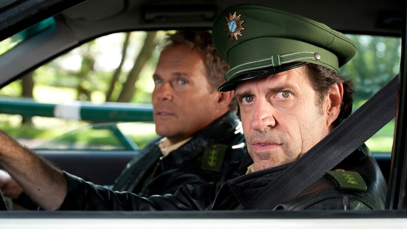 L-R: Polizeiobermeister Franz Hubert (Christian Tramitz) and Polizeiobermeister Johannes Staller (Helmfried von Lüttichau) – Bild: Die Verwendung ist nur bei redak /​ Tele München /​ © TMG und Entertainment Factory