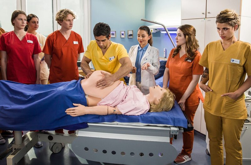 Kiran zeigt den Pflegeschülern die äußere Wendung bei einer Schwangerschaft. – Bild: ARD/​Daniela Incoronato