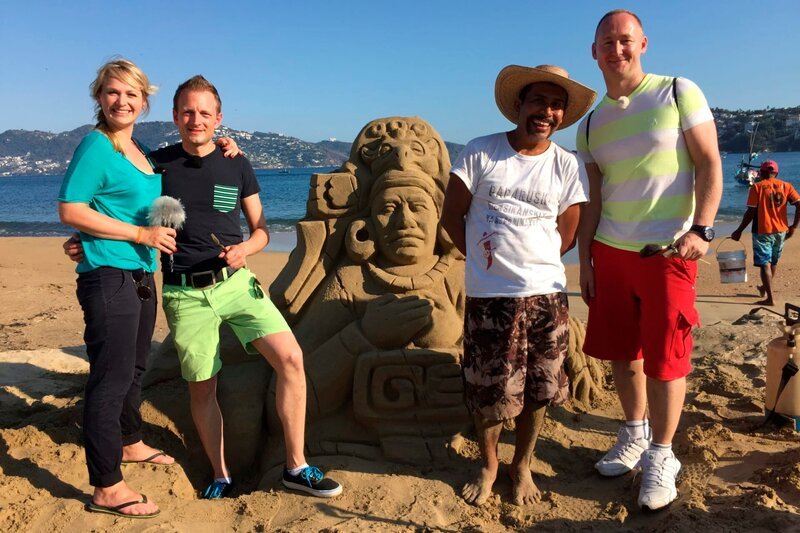 Gruppenfoto mit Sandburg und Entertainment-Managerin Cori, dem Zweiten Offizier Christian, Reiseleiter Bernd und dem Vizeweltmeister im Sandburgenbauen. – Bild: Bewegte Zeiten GmbH/​Gerrit Mannes