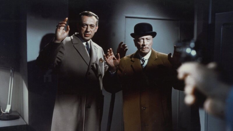 Inmitten der drängenden Ermittlungen zu einer Serie grausamer Mordfälle sehen sich Inspektor Perkins (Horst Tappert, l.) und Sir Arthur (Hubert von Meyerinck, r.) von Scotland Yard plötzlich einer gefährlichen Situation gegenüber, als sie von jemandem mit einer Waffe bedroht und gezwungen werden, ihre nächsten Schritte mit äußerster Vorsicht zu planen. – Bild: Constantin Film Inmitten der drängenden Ermittlungen zu einer Serie grausamer Mordfälle sehen sich Inspektor Perkins (Horst Tappert, l.) und Sir Arthur (Hubert von Meyerinck, r.) von Scotland Yard plötzlich einer gefährlichen Situation gegenüber, als sie von jemandem mit einer Waffe bedroht und gezwungen werden, ihre nächsten Schritte mit äußerster Vorsicht zu planen. – Bild: Constantin Film