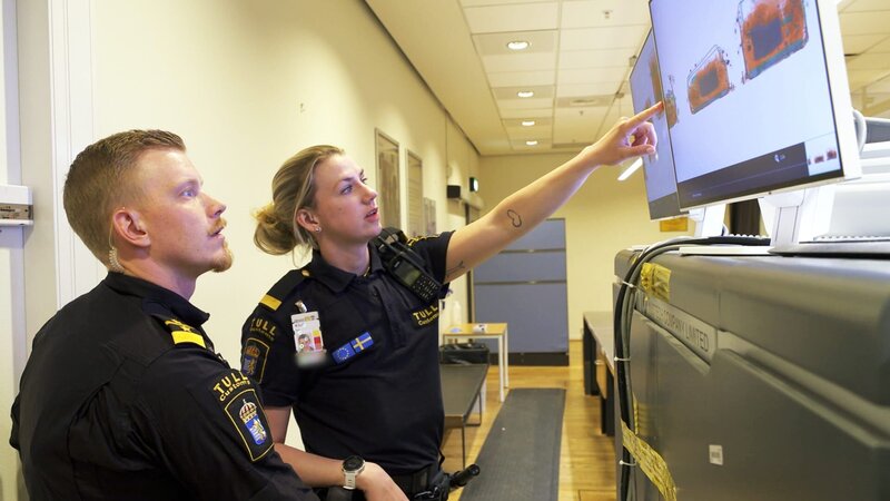 Die Grenzbeamten untersuchen den Inhalt des Koffers. – Bild: Discovery