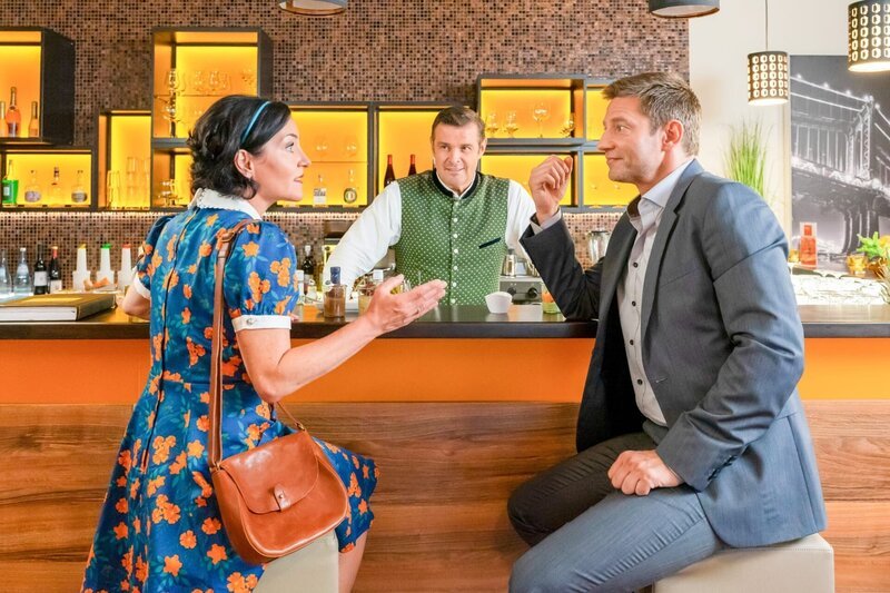 Miriam Stockl (Marisa Burger, l.) rätselt mit Kommissar Hansen (Igor Jeftić, r.) und Jo (Christian K. Schaeffer, M.), warum die Eröffnung der Trachtenboutique ausgefallen ist. – Bild: ORF/​ZDF/​Linda Gschwentner