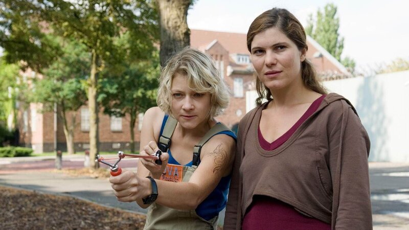 Walter hat ihre Zeit im Schutzbereich, dem „Käfig“ abzusitzen. Katja (Yasmina Djaballah, re.) will ihr mit Grit (Katrin Brockmann) eine Lektion erteilen. – Bild: TVNOW /​ Stefan Erhard