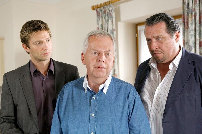 Karl Hinrichs (Harald Maack, M.) ist schockiert, als er von den Kommissaren Hansen (Igor Jeftic, l.) und Prantl (Andreas Giebel, r.) erfährt, dass seine Frau ermordet wurde. – Bild: ORF/​ZDF/​Christian A. Rieger