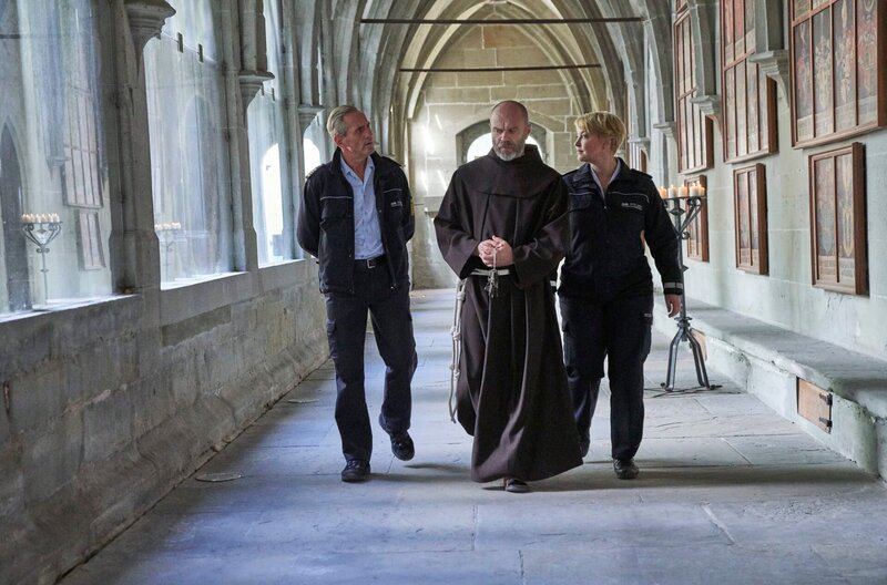 Paul Schott (Tim Wilde, l.) und Nele Fehrenbach (Floriane Daniel, r.) befragen Bruder Vadim (Attila Borlan, M.) nach Armin König. Der Autor hatte sich im Kloster Oberzell auf der Insel Reichenau einquartiert, um Recherchen für seinen neuen Roman durchzuführen. – Bild: One
