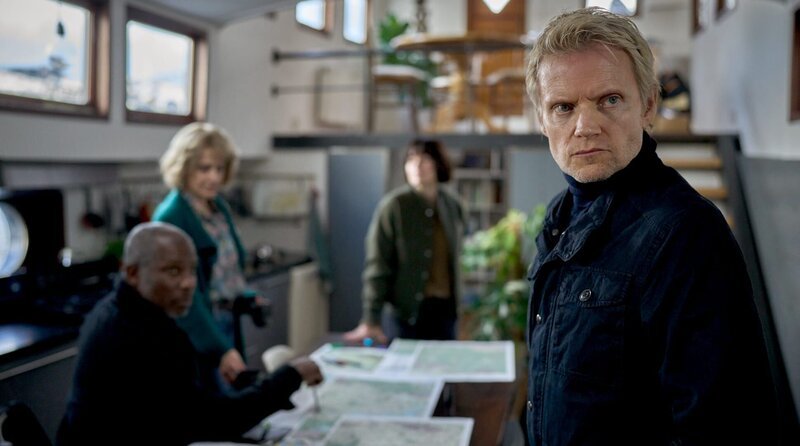 Kommissar Van der Valk (Marc Warren) bei den Ermittlungen. Im Hintergrund: Marcus Stegenga (Dennis Rudge), Anki Bergen (Raquel Cassidy) und Lucienne Hassell (Maimie McCoy). – Bild: ARD Degeto Film/​All3Media international/​Mark de Blok