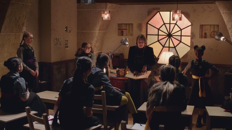 Die Vertretungslehrerin Frau Düsternis (Rachel Bell) macht tollen Unterricht. Nur Maude (Meibh Campbell, l.) und Edith (Tamara Smart, r.) wissen, dass es in Wirklichkeit ihre Freundin Mildred ist, deren Weisheitszauber sie nicht klüger, dafür aber älter gemacht hat. – Bild: ZDF/​BBC/​ZDF Enterprises