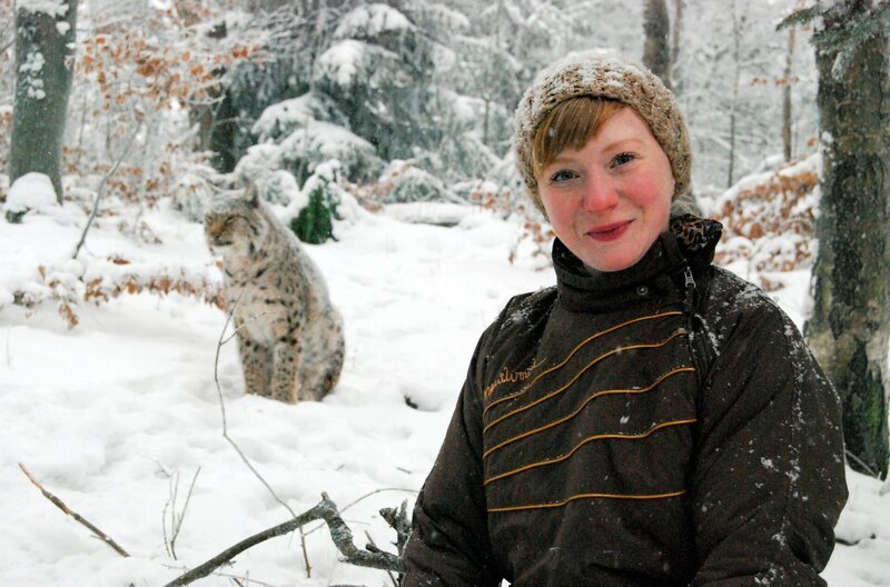 Paula im Schnee. Im Hintergrund: ein Luchs. – Bild: BR/​TEXT + BILD Medienproduktion