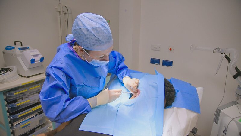 MS shot of DR Emma in scrubs performing an operation to remove Cavalli’s keloids – Bild: Warner Bros. Discovery, Inc. or its subsidiaries and affiliates