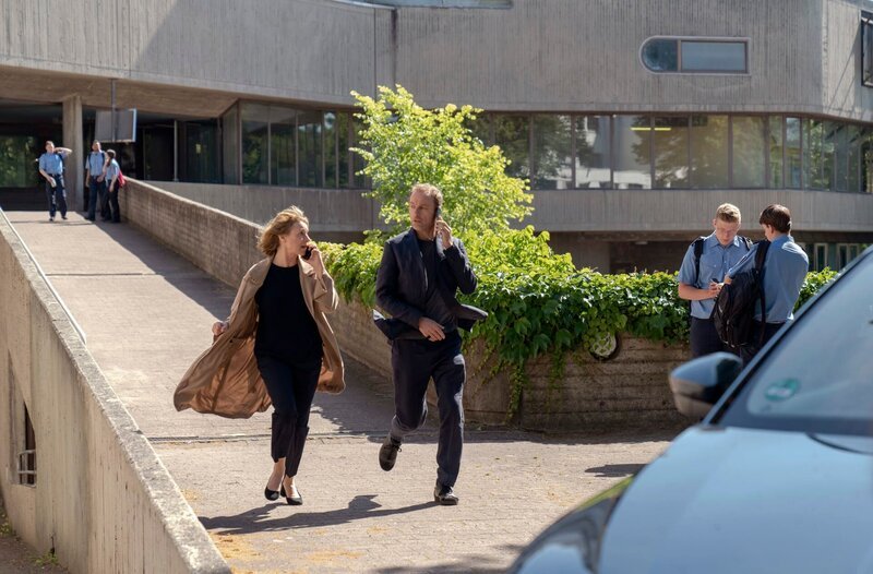 Kommissarin Susanne Bonard (Corinna Harfouch) und Kommissar Robert Karow (Mark Waschke) eilen vor der Polizeiakademie zu ihrem Auto, sie haben wichtige Informationen per Telefon erhalten. – Bild: rbb/​Marcus Glahn