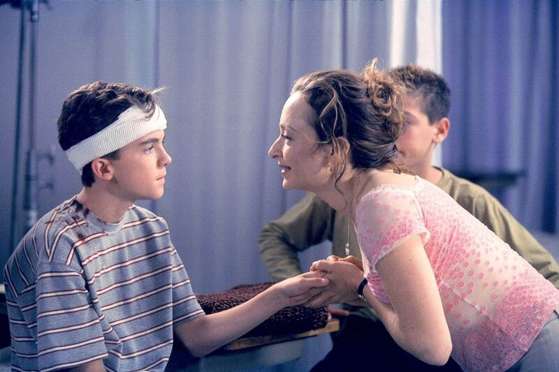 Malcolm (Frankie Muniz) wird von seiner Lehrerin Caroline (Catherine Lloyd Burns) begutachtet, nachdem er einen Kopfverband bekommen hat. – Bild: Paramount