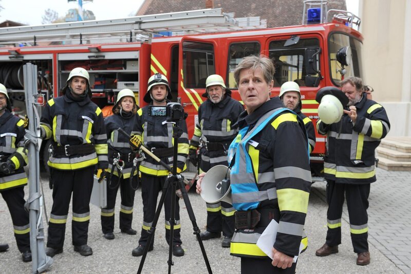 Mike, Bamberger und die Feuerwehrler starten holprig in den Imagefilm-Dreh – bis Schattenhofer plötzlich um Hilfe ruft. Von links: KLD, Mike Preissinger (Harry Blank), Veronika Brunner (Senta Auth), Florian Brunner (Tommy Schwimmer), Martin Kirchleitner (Hermann Giefer), Roland Bamberger (Horst Kummeth), KLD und Benedikt Stadlbauer (Andreas Geiss). – Bild: BR/​Marco Orlando Pichler