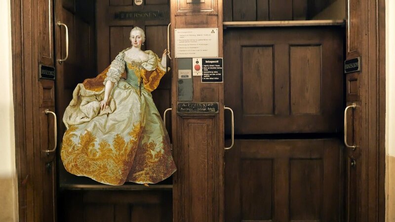 Maria Theresia war ein Aufzugsfan, aber blieb oft stecken. Sie hätte sich über einen zuverlässigen Pater Noster gefreut. Diese sind uns heute zu unsicher und es werden keine neuen mehr zugelassen. – Bild: ORF/​Familie Rockt Media