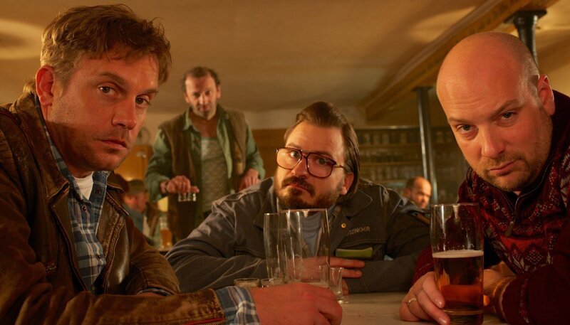 Männer unter sich: Beim „Wolfi“ finden sich Franz Eberhofer, Flötzinger und Metzger Simmerl zur regelmäßigen Bier- und Schnapsrunde ein. – Bild: ARD Degeto/​Constantin Film/​Bernd Schuller