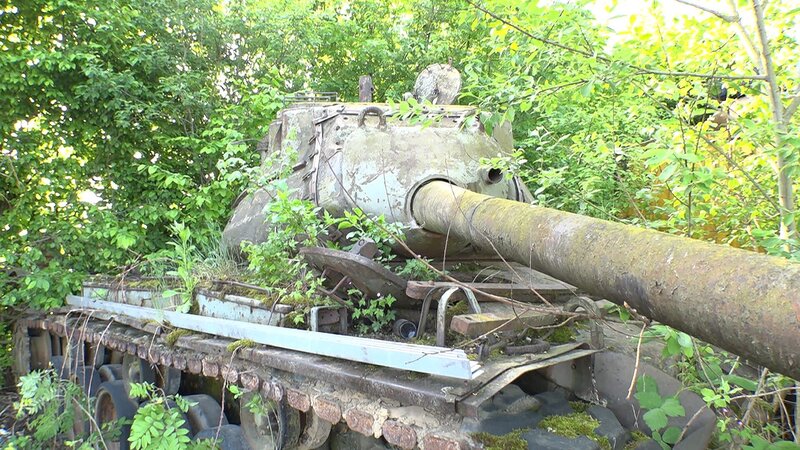 Ein verlassener Panzer im Gebüsch. – Bild: Warner Bros. Discovery