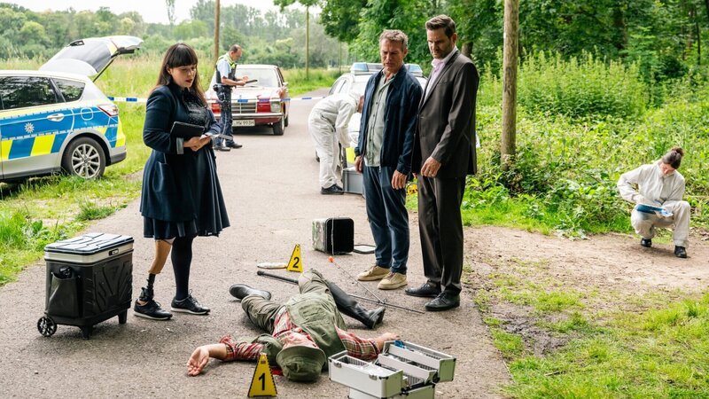 Rechtsmedizinerin Dr. Pilar Westphal (Yulia Yáńez Schmidt, l.) und die Kommissare Matti Wagner (Pierre Besson, M.) und Jonas Fischer (Lukas Piloty, r.) spekulieren, wie der tote Angler Uwe Ratke ums Leben kam – Unfall oder Mord? (Komparsen im Bild) – Bild: Martin Rottenkolber