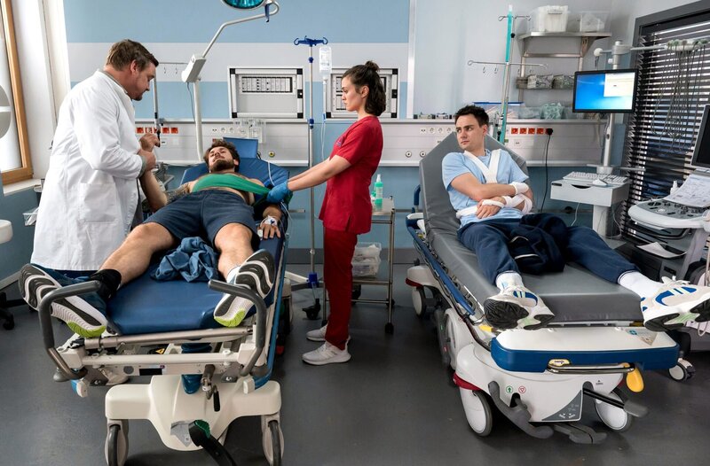 Berry Höfner (Egor Reider, 2.v.l.) und Friedrich Freitag (Pepe Harder, r.) haben sich bei einem Rugby-Spiel verletzt und werden in der Notaufnahme von Marc Lindner (Christian Beermann, l.) und Rebecca Krieger (Milena Straube, 2.v.r.) versorgt. – Bild: ARD/​Jens-Ulrich Koch