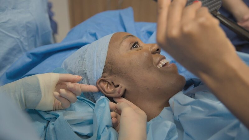 Close up of Samantha on clinic bed post surgery looking in mirror and smiling. Ep3. – Bild: 2021, Discovery, Inc. All Rights Reserved.