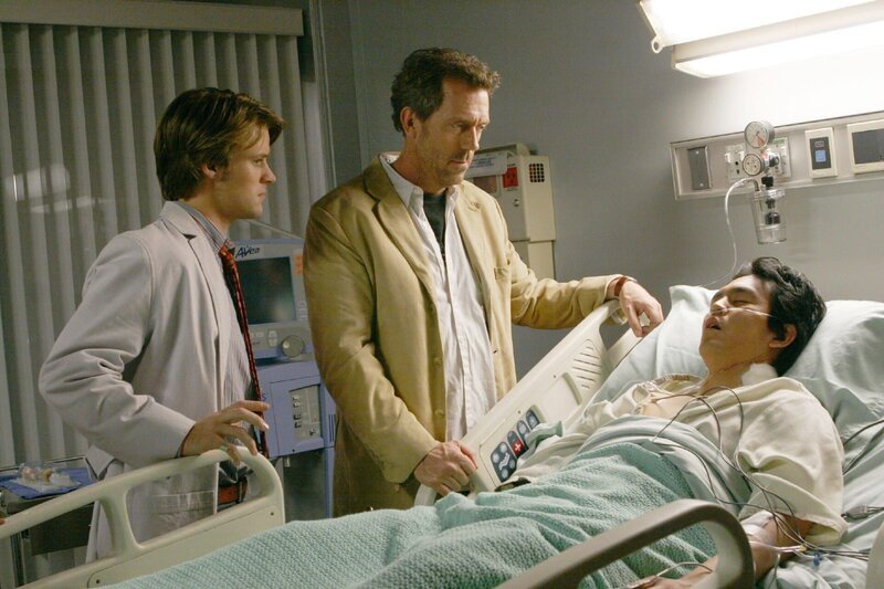 Nach einem weiteren Schlaganfall ist der junge Harvey Park (John Cho, lieg.) ins Koma gefallen. Dr. House (Hugh Laurie, M.) und Dr. Chase (Jesse Spencer) vermuten, dass Harvey Verwachsungen in den Halsschlagadern hat und wollen operieren. – Bild: NBC Universal Inc.