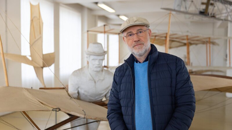 Harald Lesch vor einem Nachbau des berühmten Fluggleiters von Otto Lilienthal. Die Geschichte der Fliegerei, wie auch die heutigen Konsequenzen der massenhaften Nutzung werden ebenfalls thematisiert. – Bild: ZDF und Hans Jakobi./​Hans Jakobi