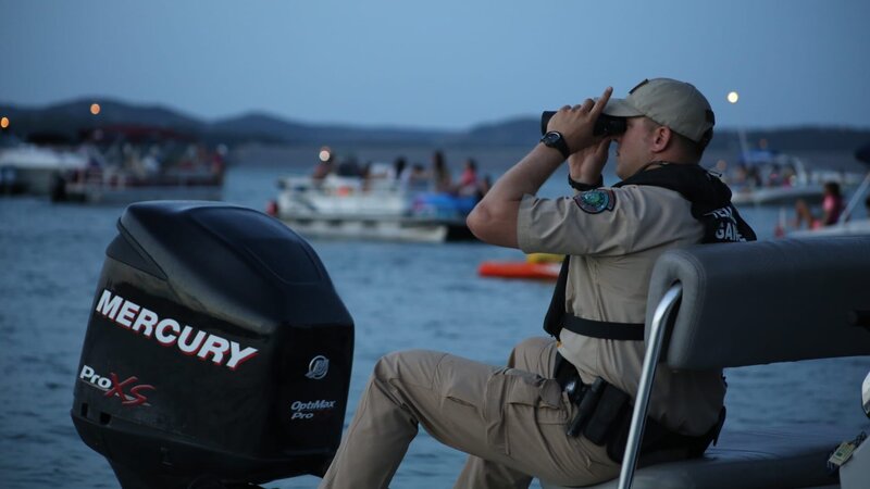 Warden McGinley on boat looking through binoculars. – Bild: Discovery Communications