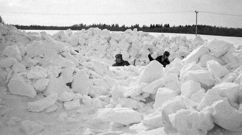 Originalaufnahme vom Katastrophenwinter 1978/​79 auf Rügen. Zwei Männer kämpfen sich durch die Schneemassen. – Bild: MDR/​Saxonia Entertainment/​Egon Nehls