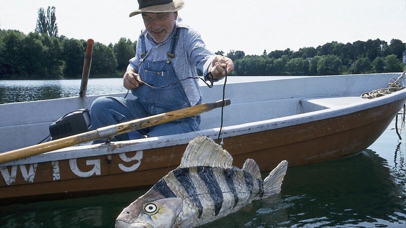 Peter (Peter Lustig) hat sich einen großen Fisch gebastelt. Im Inneren des Fisches steckt eine Kamera. Peter wird den Fisch schwimmen lassen, vielleicht erhält er so Fotos von dem Bärstädter See-Monster. – Bild: ZDF und Christiane Pausch./​Christiane Pausch