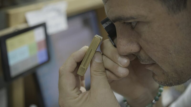 Ein Mann prüft die Qualität von Gold. – Bild: Warner Bros. Discovery