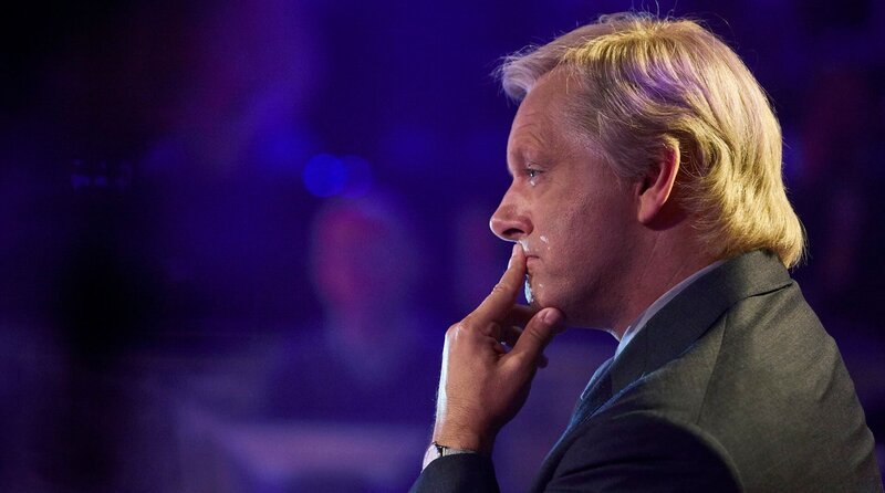 Chris Tarrant (Michael Sheen) stellt dem Teilnehmer auf dem heißen Stuhl die Quizfragen. – Bild: WDR/​Sony Pictures Connect Inc.
