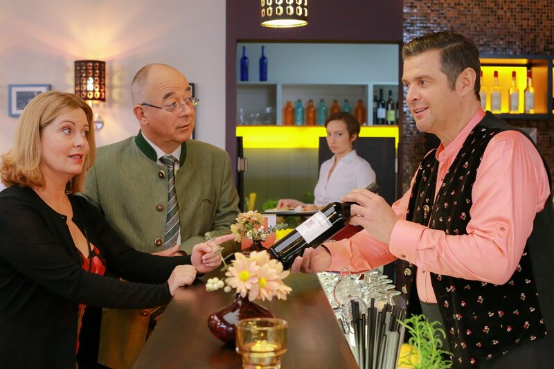 Jo (Christian K. Schaffer, r.) empfiehlt Marie (Karin Thaler, l.) und Herrn Achtziger (Alexander Duda, 2.v.l.) einen Wein als Prâsent, was Mitarbeiterin Steffi (Regina Speiseder, 2.v.r.) skeptisch beobachtet. – Bild: Christian A. Rieger – klick /​ ZDF /​ Die Verwendung ist nur bei redaktioneller Berichterstattung im Rahmen einer Programmankündigung ab 2 Monate vor der ersten Auss /​ © ZDF/​Christian A. Rieger – klick