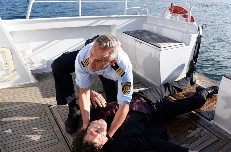 Der schwerverletzte Victor Eder (Harald Schröpfer, unten) wird bewusstlos und in voller Montur mitten auf dem Bodensee von Paul Schott (Tim Wilde, oben) vor dem Ertrinken gerettet. Die Umstände setzen Ermittlungen in Gang. – Bild: „Bild: ARD/​Laurent Trümper (S2+). ARD Programmdirektion/​Bildredaktion