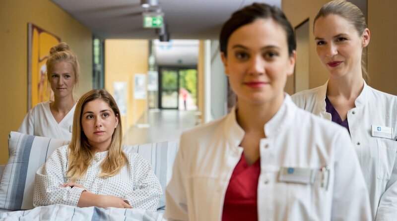 Die Assistenzärztin Dr. Rebecca Krieger (Milena Straube, 2.v.r.) ist begeistert, als sie hört, dass sie am „Umgekehrt-Tag“ wie eine Fachärztin den Ton angeben darf, denn sie ist mit ihrer Schwester Dr. Julia Berger (Mirka Pigulla, r.) zu einem spannenden Fall eingeteilt. Für Luisa Fuchs (Sarah Buchholzer, 2.v.l. mit Komparsin) steht die Operation einer Nierenbeckenplastik an. – Bild: ARD/​Jens-Ulrich Koch