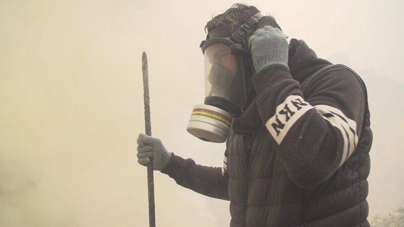 Ausgerüstet mit einer Atemschutzmaske und einem langen Metallstab versucht sich Sebastian Perez Pezzani als Schwefelstecher. – Bild: ZDF und Capa /​ 13ičme Rue.