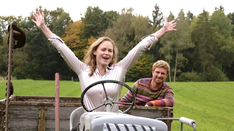 Sie kann es: Ella (Inez Bjørg David) nimmt Florian (Leo Reisinger) auf dem Traktor mit. – Bild: ARD Degeto/​Kerstin Stelter