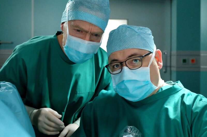 Hans-Peter Brenner (Michael Trischan, rechts) freut sich, dass er seine erste eigene Operation durchführen darf. Dass diese ausgerechnet unter Kaminskis (Udo Schenk, links) Obhut stattfindet, ist das weniger Erfreuliche daran. Brenner hat sich ausführlich auf den anstehenden Eingriff vorbereitet, doch dann wurde ein anderer Patient eingeschoben und natürlich eine andere OP anberaumt. Brenners Selbstbewusstsein ist am Boden. Wird er sich und der Ärzteschaft unter diesen Umständen endlich beweisen, dass er ein guter Chirurg werden kann? – Bild: BR/​MDR/​Sebastian Kiss /​ Sebastian Kiss