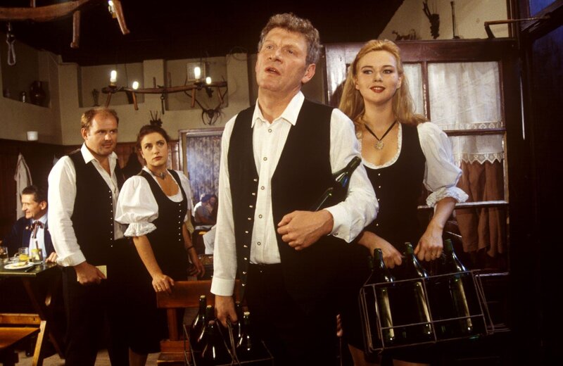 Wirt Hans Felsner und seine Schwägerin Gerda Felsner kommen gut gelaunt aus dem Weinkeller in die Wirtsstube zurück. Seine Frau Helga und der Kellner finden ihr Verhalten verdächtig. – Bild: SAT.1 /​ Ali Schafler