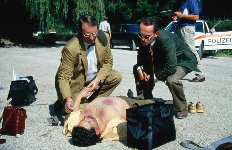Kriminalassistent Stockinger (Karl Markovics, r.) und der Gerichtsmediziner Dr. Graf (Gerhard Zemann, l.) untersuchen die Leiche eines Mannes, der in einer Mülltonne gefunden wurde. Kommissar Moser glaubt, dass ein Verbrecher-Ring hinter dem Mord steckt … – Bild: SAT.1