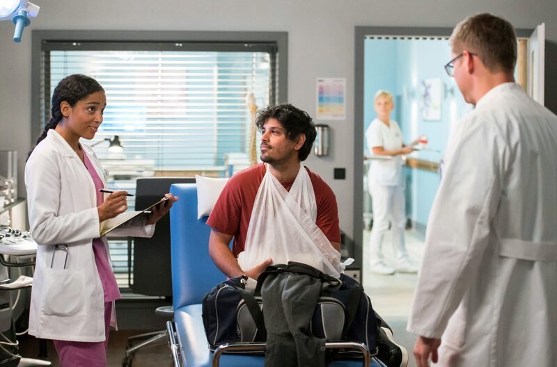 Emma (Elisa Agbaglah, l.) und Elias (Stefan Ruppe, r.) kümmern sich um ihren aufgeweckten Patienten Alexander Haag (Daniel Popat, M.). – Bild: ARD/​Jens Ulrich Koch