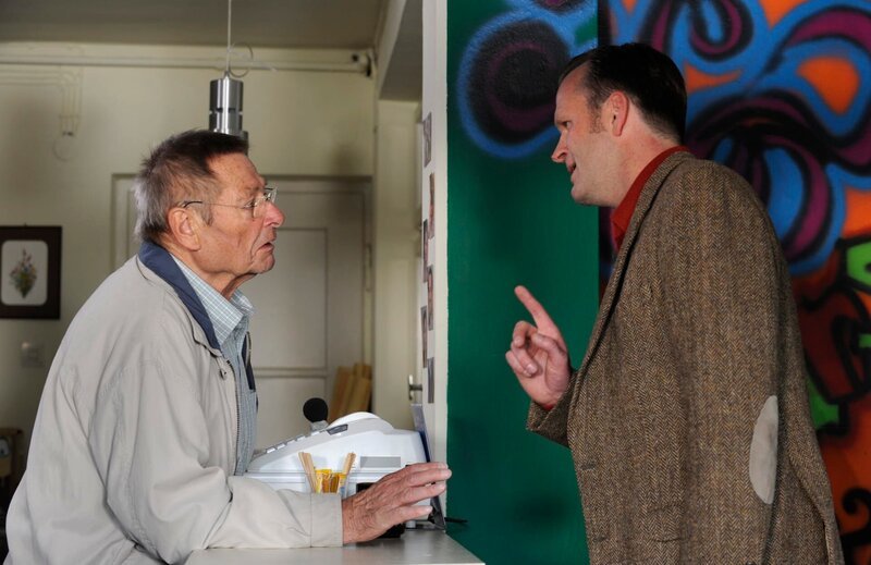 Alois bekommt seine Lektion, als wegen seiner schlechten Laune ein Marktforscher mit der Auflösung des Poststellen-Vertrags droht. Von links: Alois Preissinger (Erich Hallhuber sen.) und der Post-Marktforscher (Falk Rößler). – Bild: Marco Orlando Pichler /​ BR