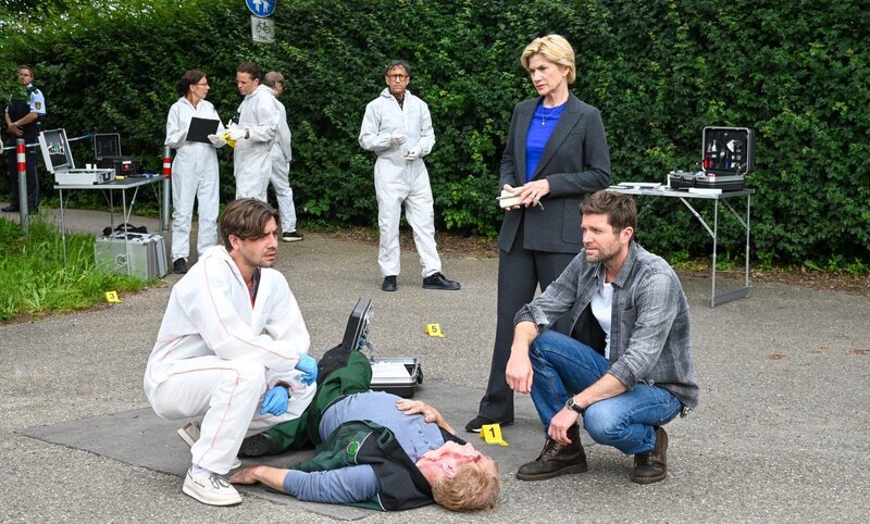 Der Gärtner Christian Schwarz (Komparse, liegend) stirbt an plötzlichem Herzversagen. Rechtsmediziner Dr. Benedikt Förster (Florian Wünsche, l.) äußert gegenüber den Kriminalkommissaren Martina Seiffert (Astrid M. Fünderich) und Jo Stoll (Peter Ketnath, r.) den Verdacht, dass der Mann vergiftet wurde. Findet die Spurensicherung (Komparsen) rund um Jan Arnaud (Mike Zaka Sommerfeldt, Hintergrund 3.v.r.) entsprechend relevante Spuren? – Bild: MARKUS_FENCHEL /​ ZDF