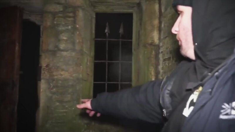 Der Mann zeigt auf die dunkle Tür. – Bild: Warner Bros. Discovery